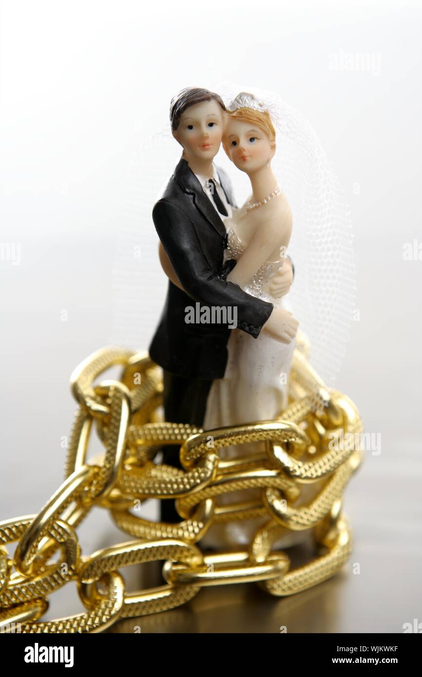 Metapher der Ehe als ein Verlust an Freiheit. Hochzeit-Figuren und goldene Kette Stockfoto