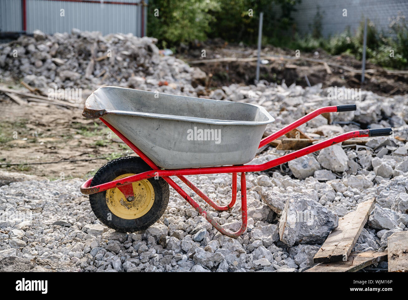 Schubkarre auf dem Hintergrund der Bauschutt aus Beton und alte Bretter Stockfoto