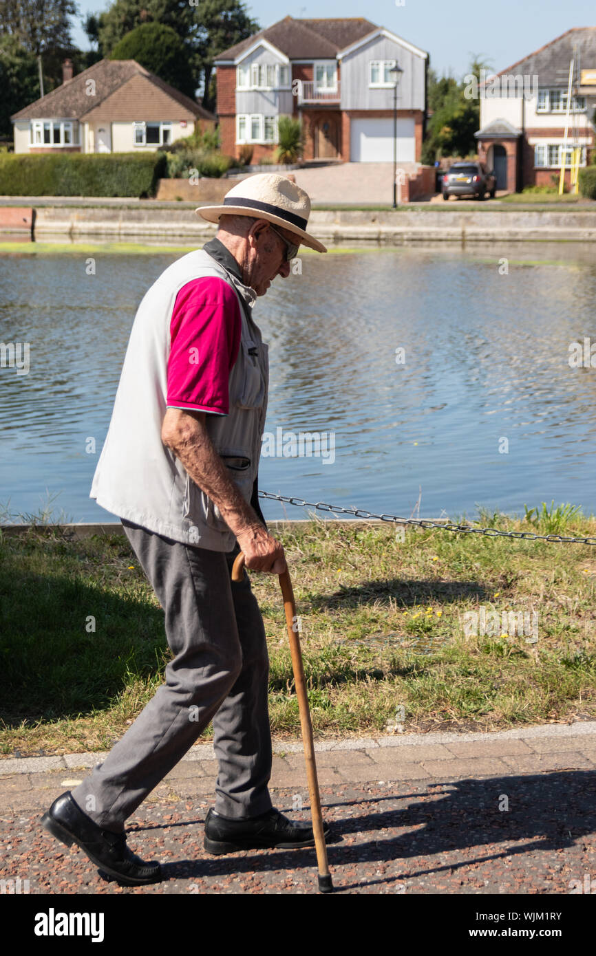 Ein älterer Mann bei einem Spaziergang mit einem Stock oder Gehstock Stockfoto