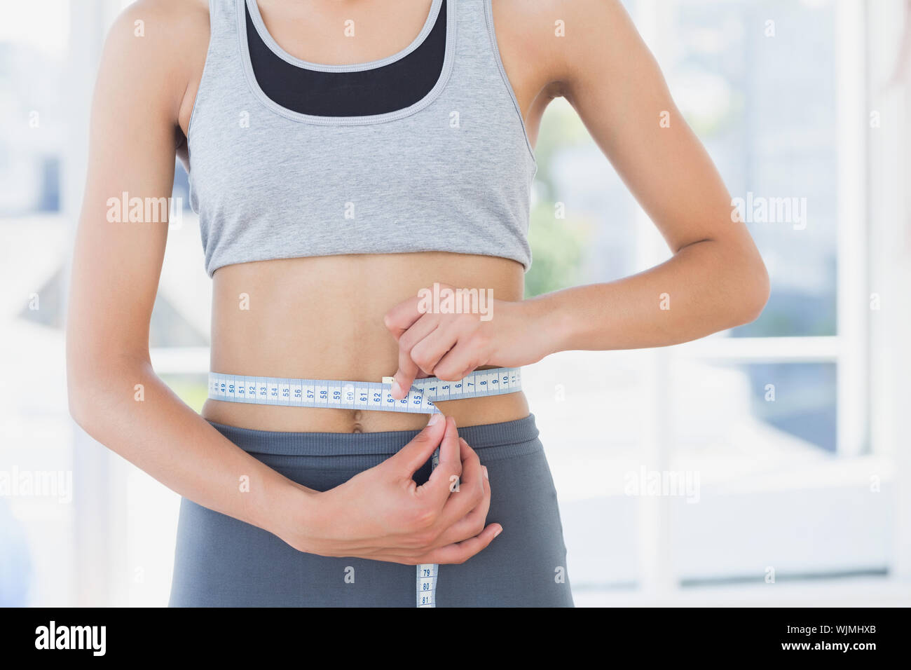 Closeup mittleren Abschnitt der sportliche junge Frau ihre Taille messen im Fitness Studio. Stockfoto
