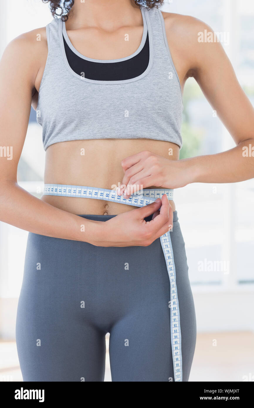 Closeup mittleren Abschnitt der sportliche junge Frau ihre Taille messen im Fitness Studio. Stockfoto