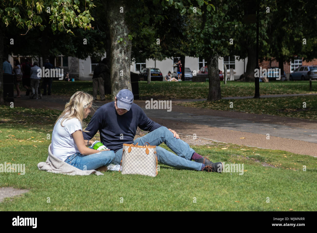 Ein paar Sat im Park auf der Wiese in der Sonne an einem Sommertag mit Mittagessen Stockfoto