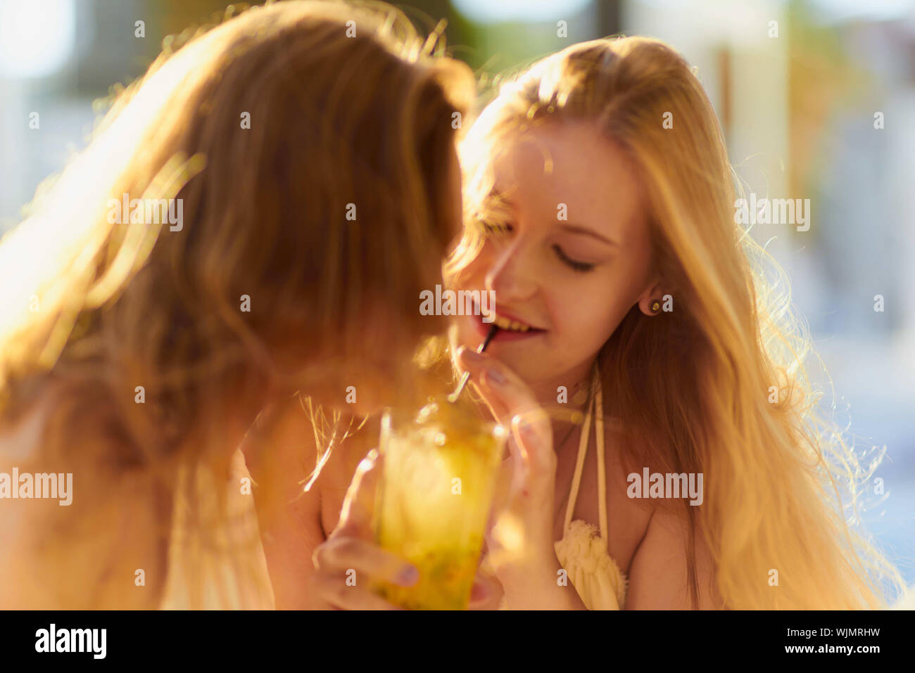 Sonnenlicht fällt auf junge Frau trinkt Trinken von Freund Stockfoto