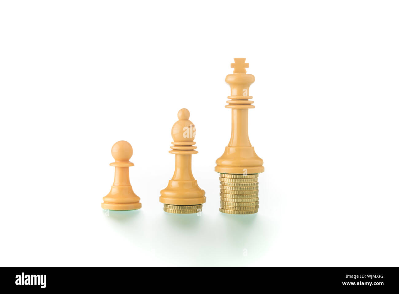 Konzeptionelle und metaphorische Fotografie mit Schachfiguren und Münzen auf weißem Hintergrund zeigt das Konzept der sozialen und wirtschaftlichen Realität. Stockfoto