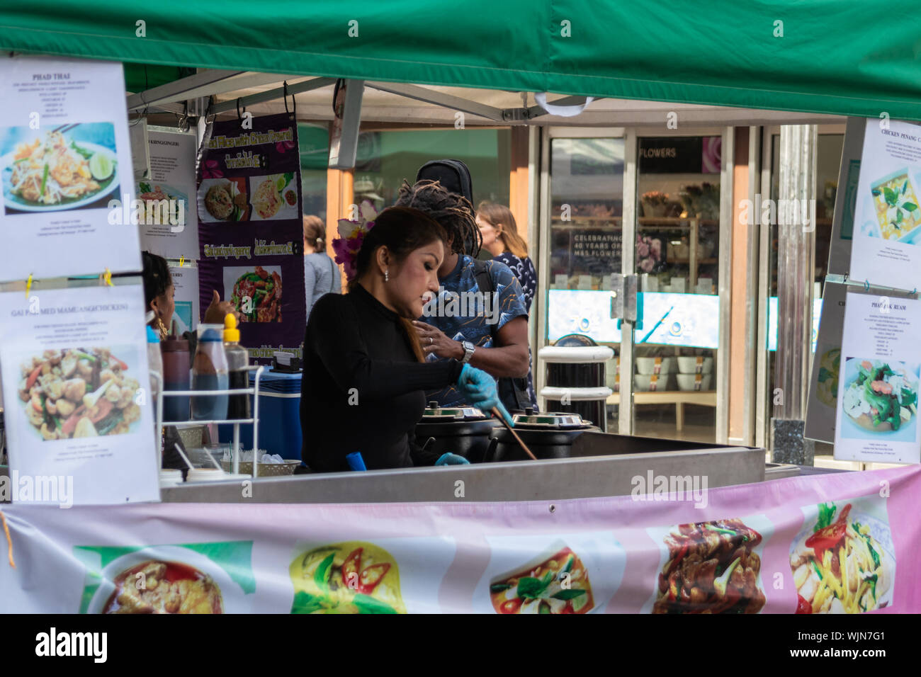 Winchester, Hampshire, UK ein Thai Lady kochen Street Food am Marktstand zum öffentlichen Verkauf Stockfoto
