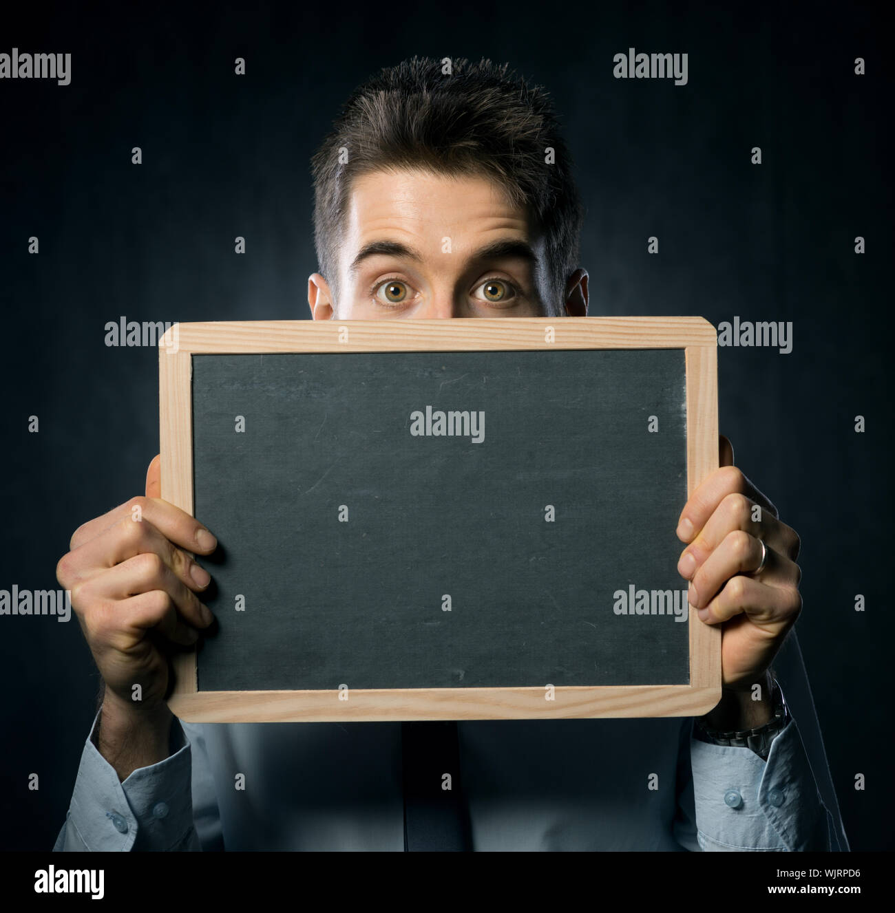 Schönen jungen Mann mit hochgezogenen Augenbrauen hält eine Tafel. Stockfoto