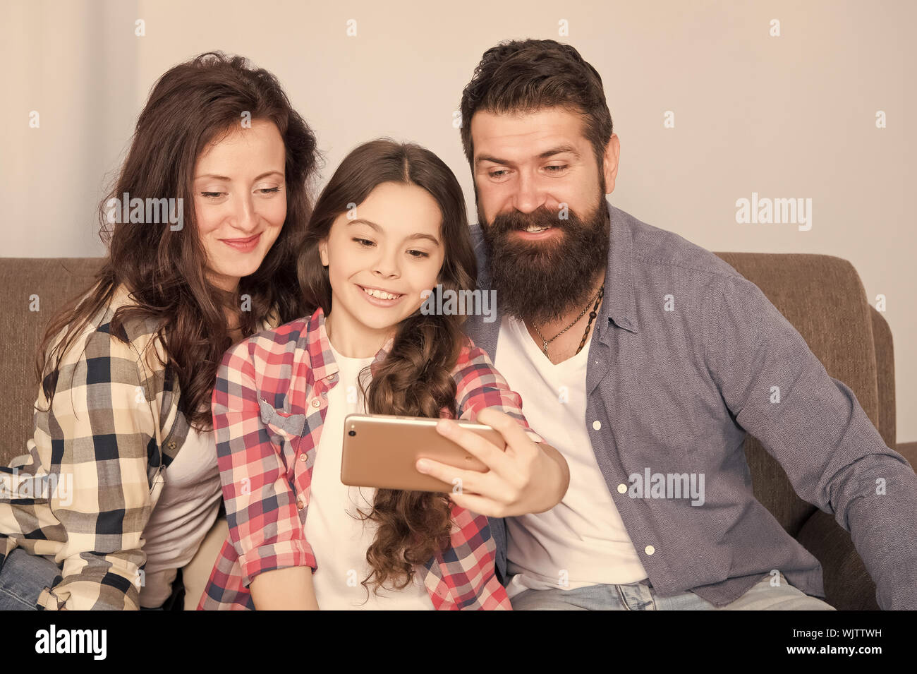 Familie selfie. Familie verbringen Wochenende zusammen. Verwendung des Smartphones für selfie. Freundliche Familie gemeinsam Spaß zu haben. Mama, Papa und Tochter entspannt auf einer Couch. Familie posieren für Fotos. Glückliche Momente festzuhalten. Stockfoto