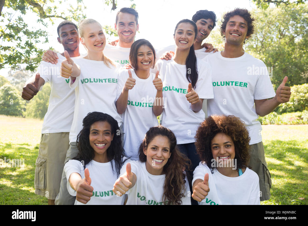 Group Portrait von zuversichtlich freiwillige Gestik Daumen hoch in Park Stockfoto