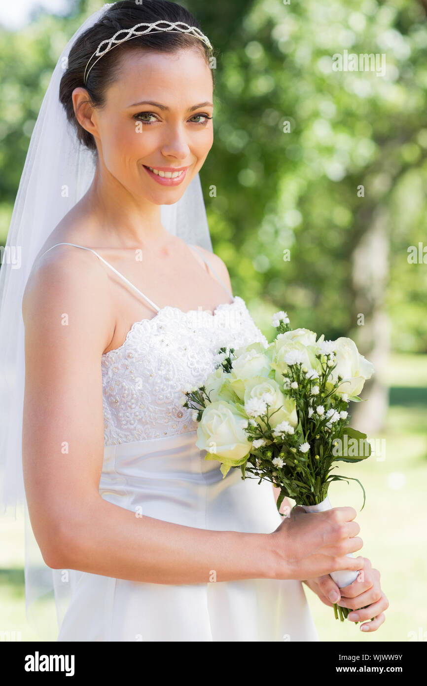 Portrait von zuversichtlich Braut holding Blumenstrauß im Garten Stockfoto