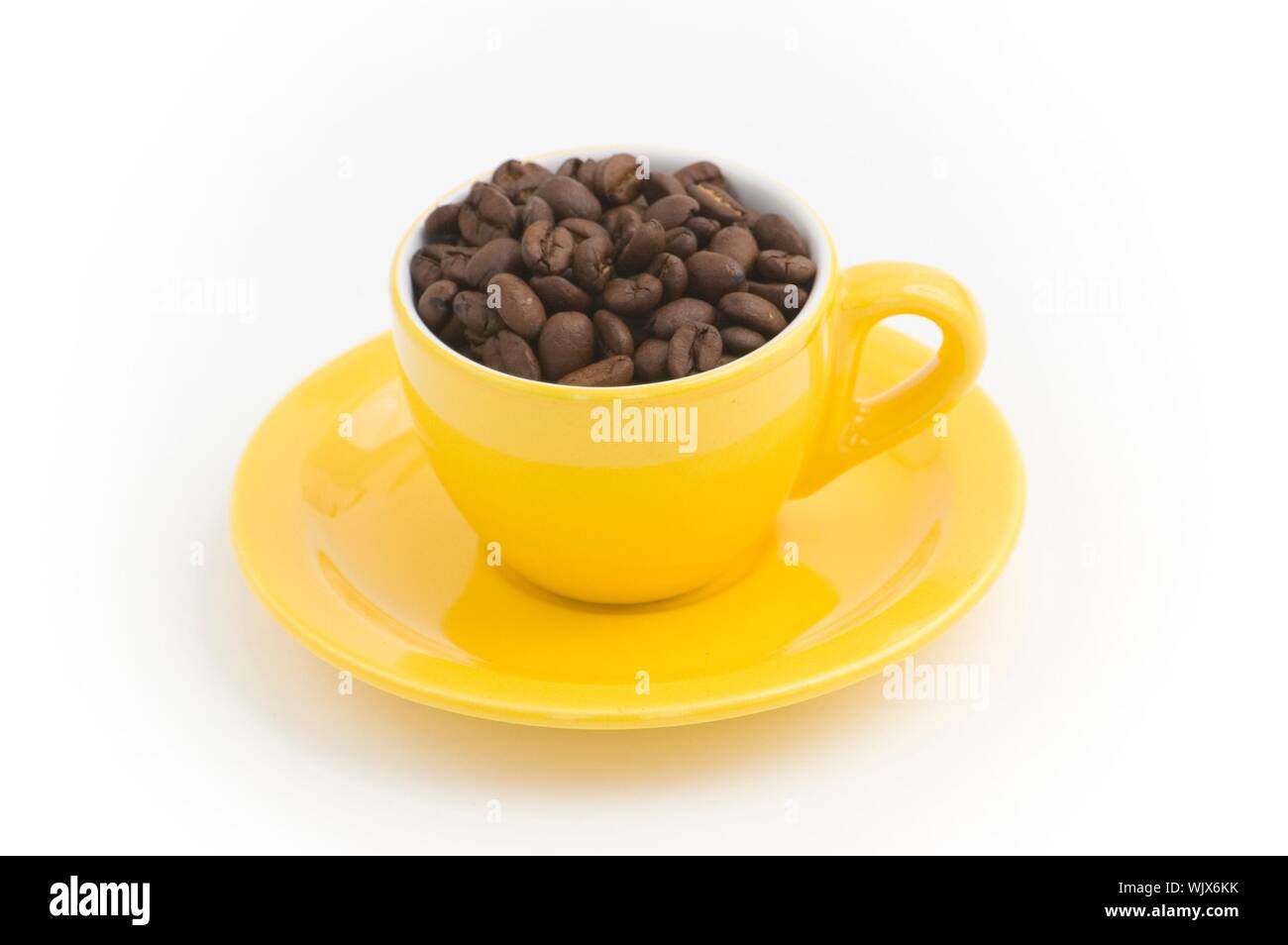 Gelbe Espressotasse mit Kaffeebohnen gefüllt Stockfoto