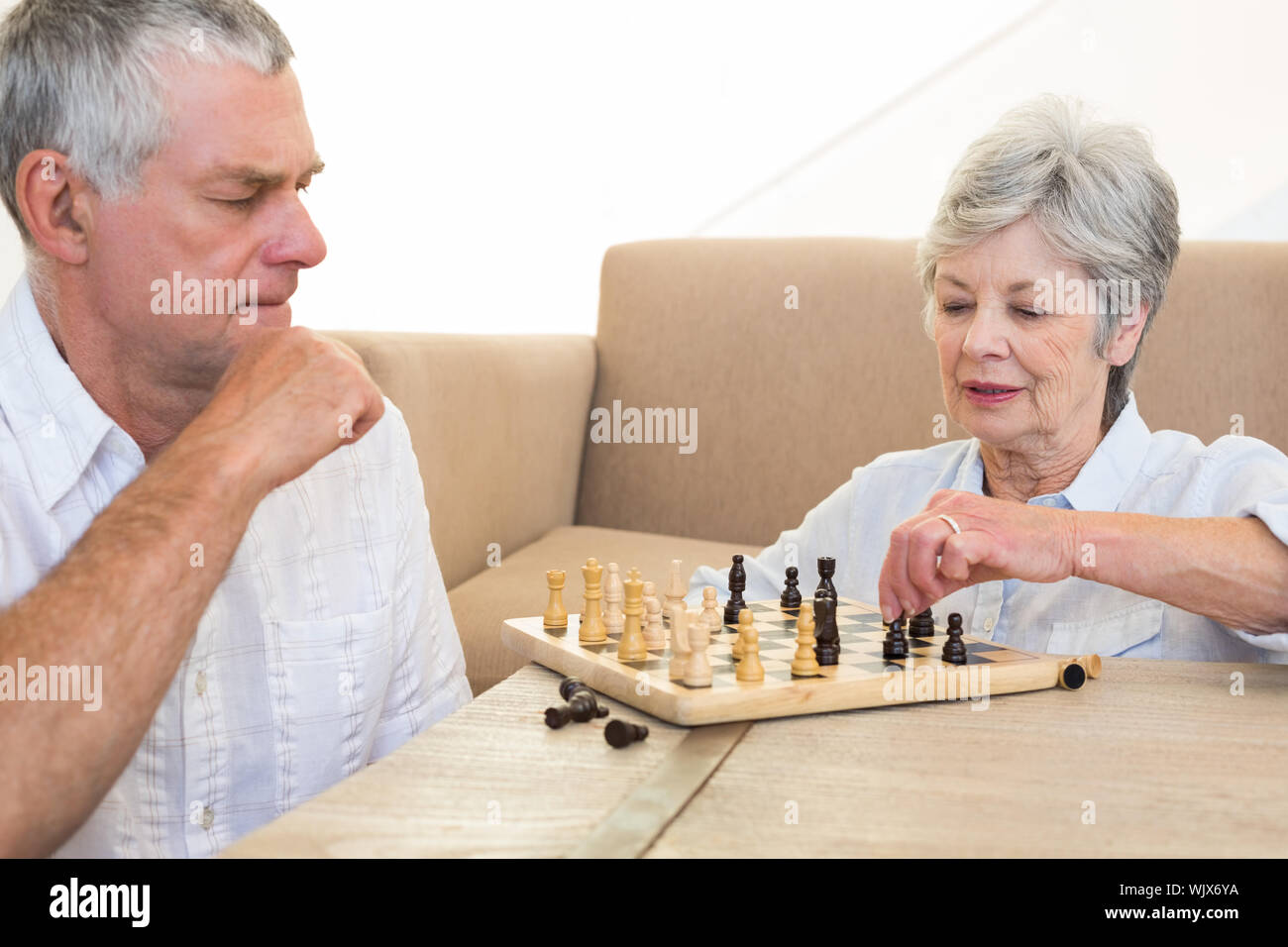 Senior Paar auf, Schach spielen zu Hause sitzen im Wohnzimmer Stockfoto