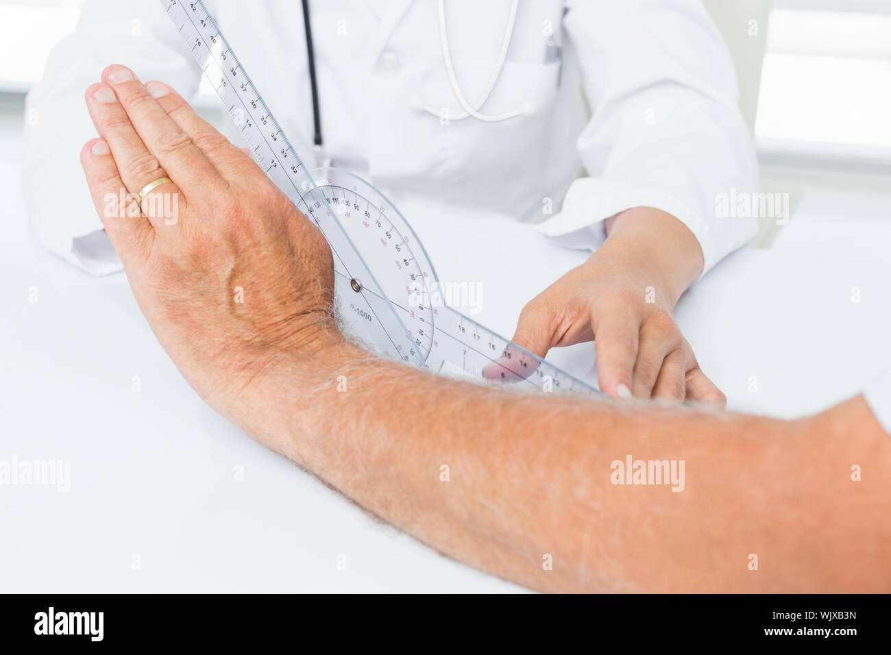 Close-up mittleren Abschnitt eines Physiotherapeuten untersuchen Patienten Handgelenk mit goniometer Medizinisches Büro Stockfoto