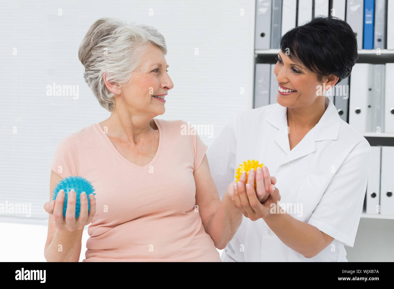 Ärztin mit älteren Patienten mit Stress Buster Kugeln an der medizinischen Büro Stockfoto