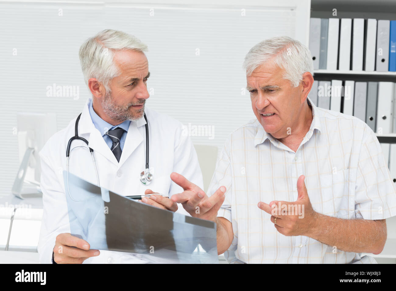Männlicher Arzt erklären, x-ray Bericht zu den älteren Patienten in der Arztpraxis Stockfoto
