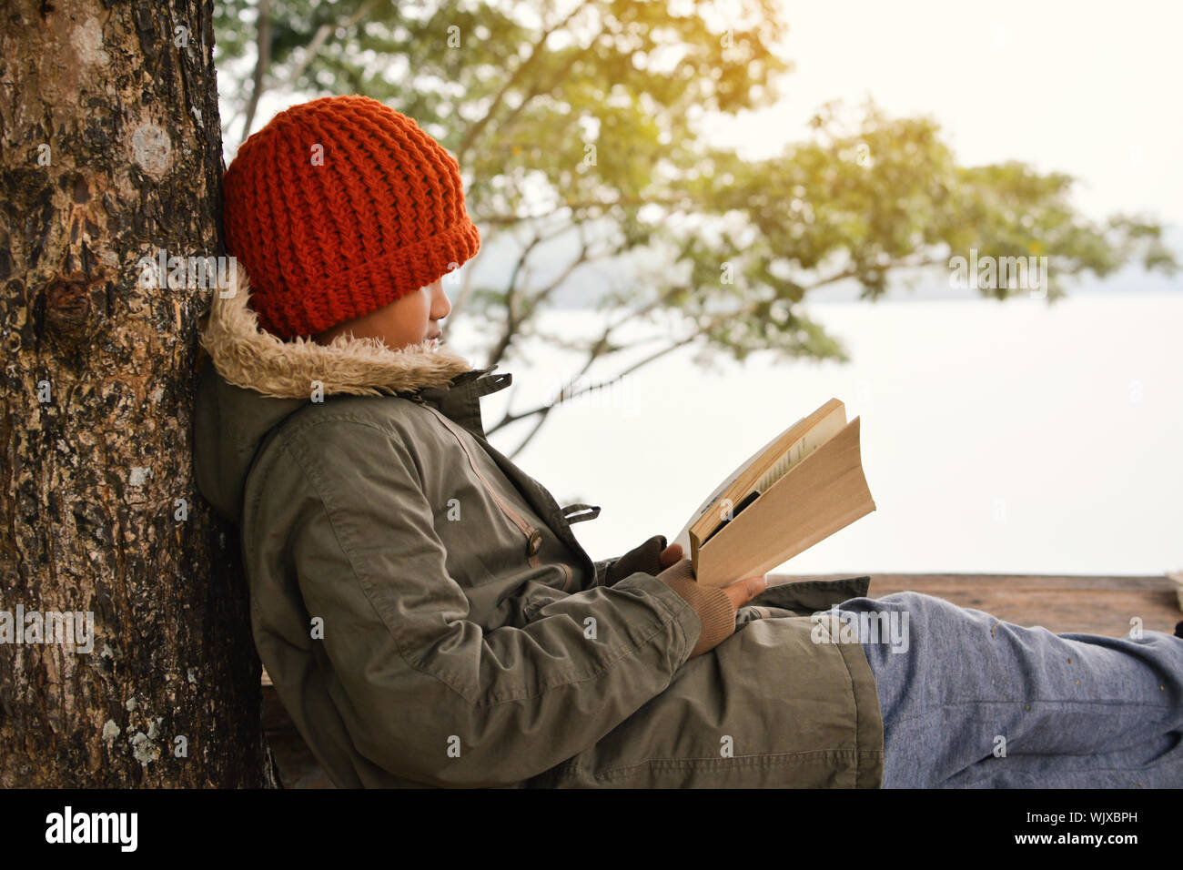 Junge lesen Buch beim Sitzen auf der Werkbank Stockfoto