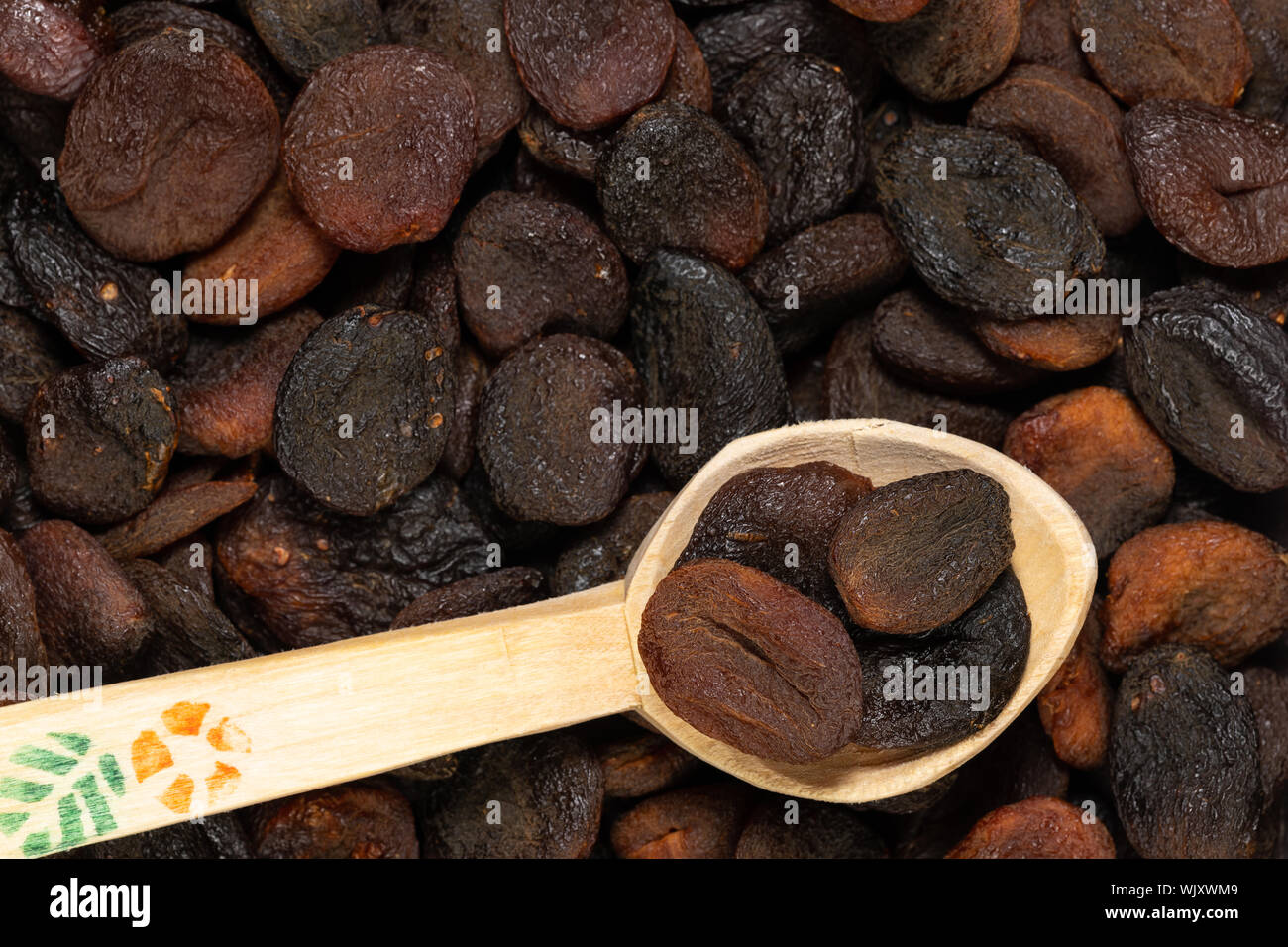 Nahaufnahme von dunkelbraun gefärbt Aprikosen in eine hölzerne Schaufel mit selektiven Fokus getrocknet. Stockfoto