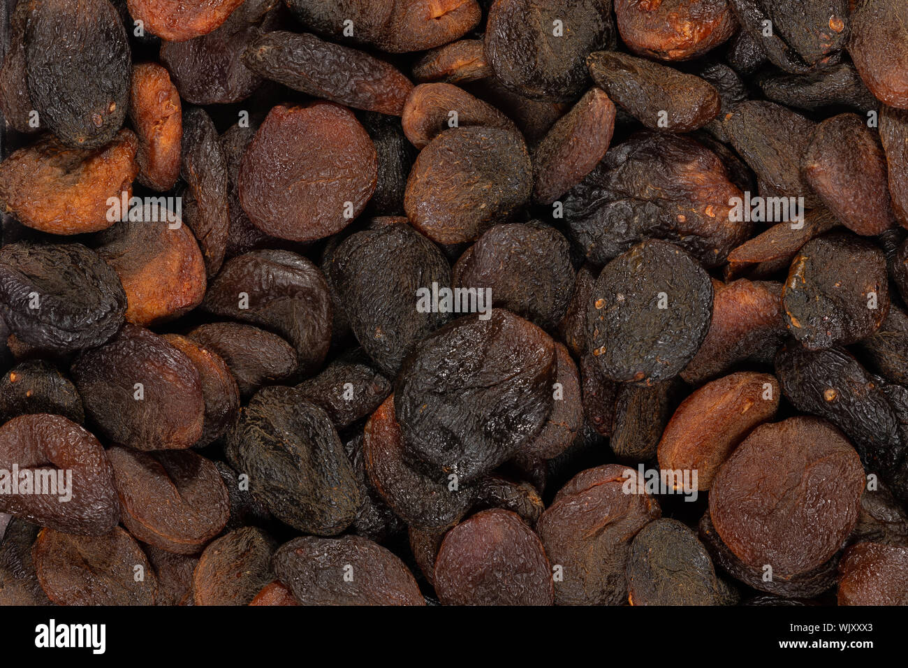 Nahaufnahme von dunkelbraun gefärbt getrocknete Aprikosen Hintergrund Textur. Stockfoto