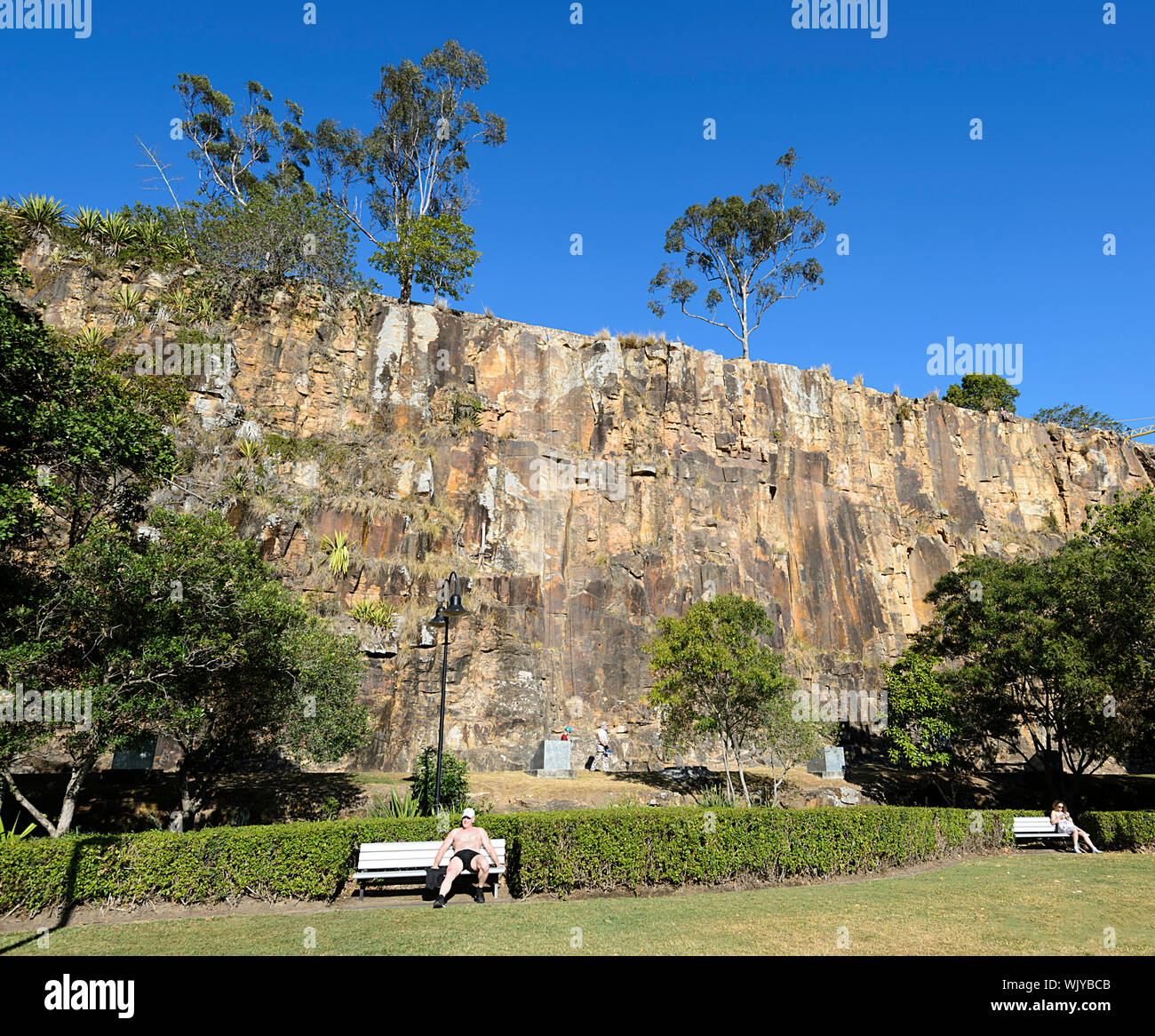 Zwei Personen beim Sonnenbaden auf einer Bank in einem Park am Kangaroo Point Cliffs, Brisbane, Queensland, Queensland, Australien Stockfoto