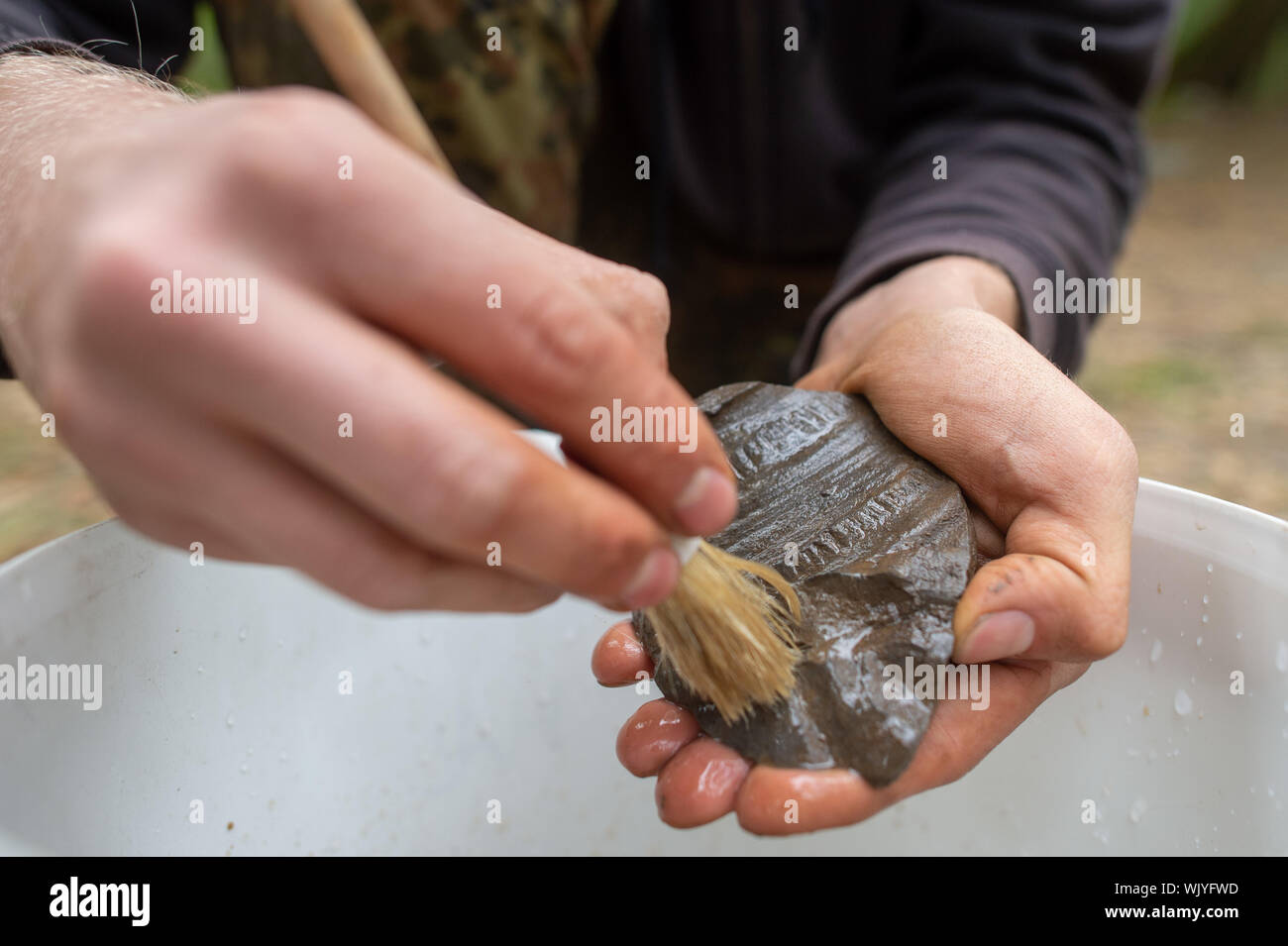 03 September 2019, Sachsen-Anhalt, Güntersberge: Eine Archäologie student reinigt eine dekorierte Shard an der Ausgrabungsstätte "Wüstung Anhalt'. Die Siedlung bedeckt etwa 11 Hektar und wurde zwischen dem 11. und dem 12. Jahrhundert gegründet. Das Dorf verlassen wurde bereits im 15. Jahrhundert. Das Dorf ist eine von ungefähr 100 im Harz, die während des Mittelalters verschwunden und sind nun verlassenen Gebieten genannt. Die Ausgrabungen sind wichtig, weil es kaum haben systematische Untersuchungen im östlichen Harz so weit gewesen. (Dpa' findet von verlorenen Dorf in der Nähe von ballenstedt vorgestellt werden') Stockfoto