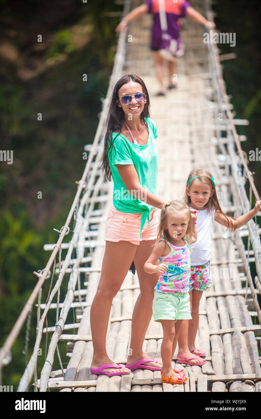 Kleine Mädchen und junge Frau, die zu Fuß auf der Hängebrücke über den Fluss Loboc, Philippinen Stockfoto