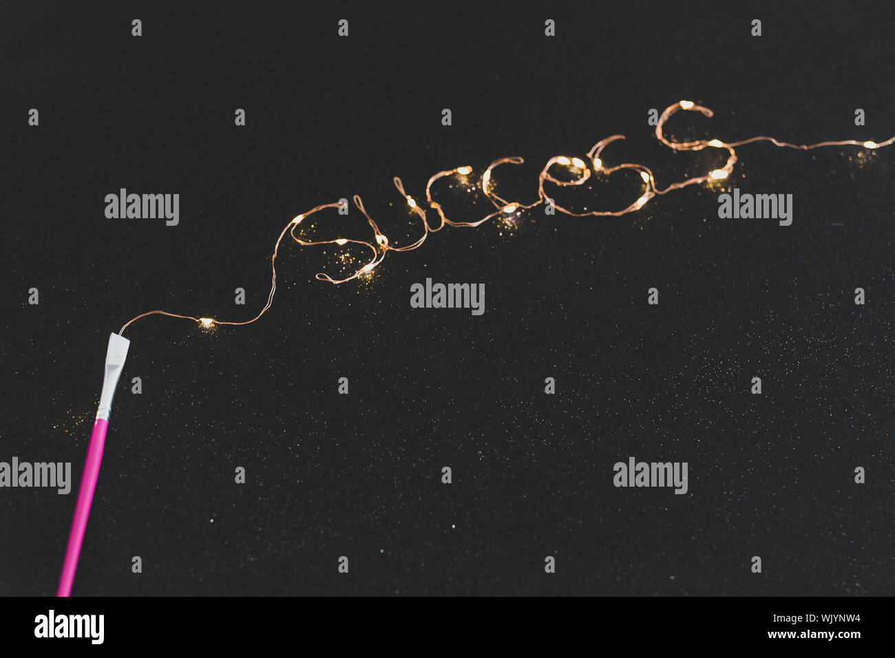 Pinsel malen Erfolgsmeldung aus Lichterketten auf dunklen glitzerndem  Hintergrund, konzeptionelle Still Life Stockfotografie - Alamy