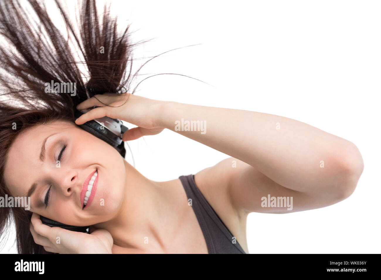 Lächelnde hübsche Brünette wirft ihr Haar beim Musikhören Stockfoto