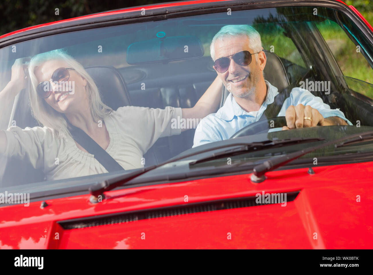 Gerne älteres Paar im roten Cabrio Stockfoto