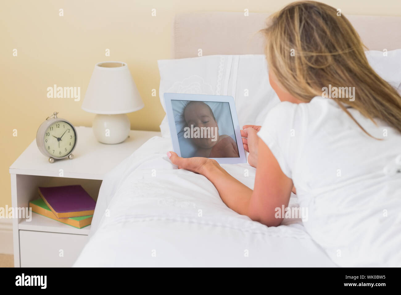Frau mit einem Tablet-pc auf ihrem Bett liegend konzentriert Stockfoto