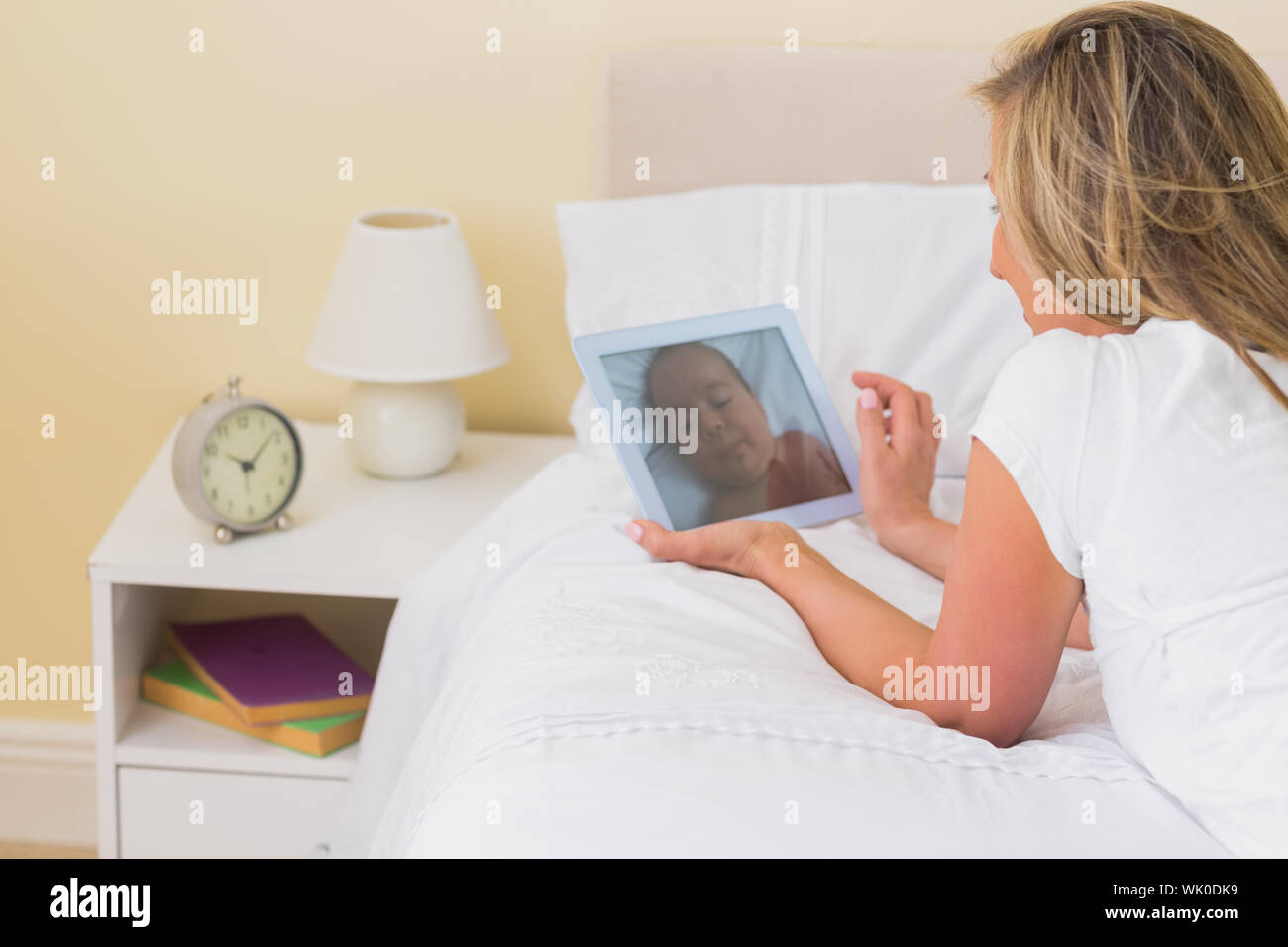 Nachdenkliche Frau mit einem Tablet-pc auf ihrem Bett liegend Stockfoto