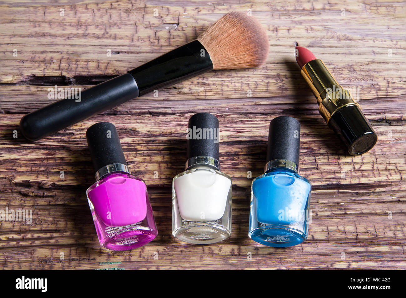 Hohe Betrachtungswinkel von Nagellack Flaschen mit Lippenstift und Make-up-Pinsel auf hölzernen Tisch Stockfoto