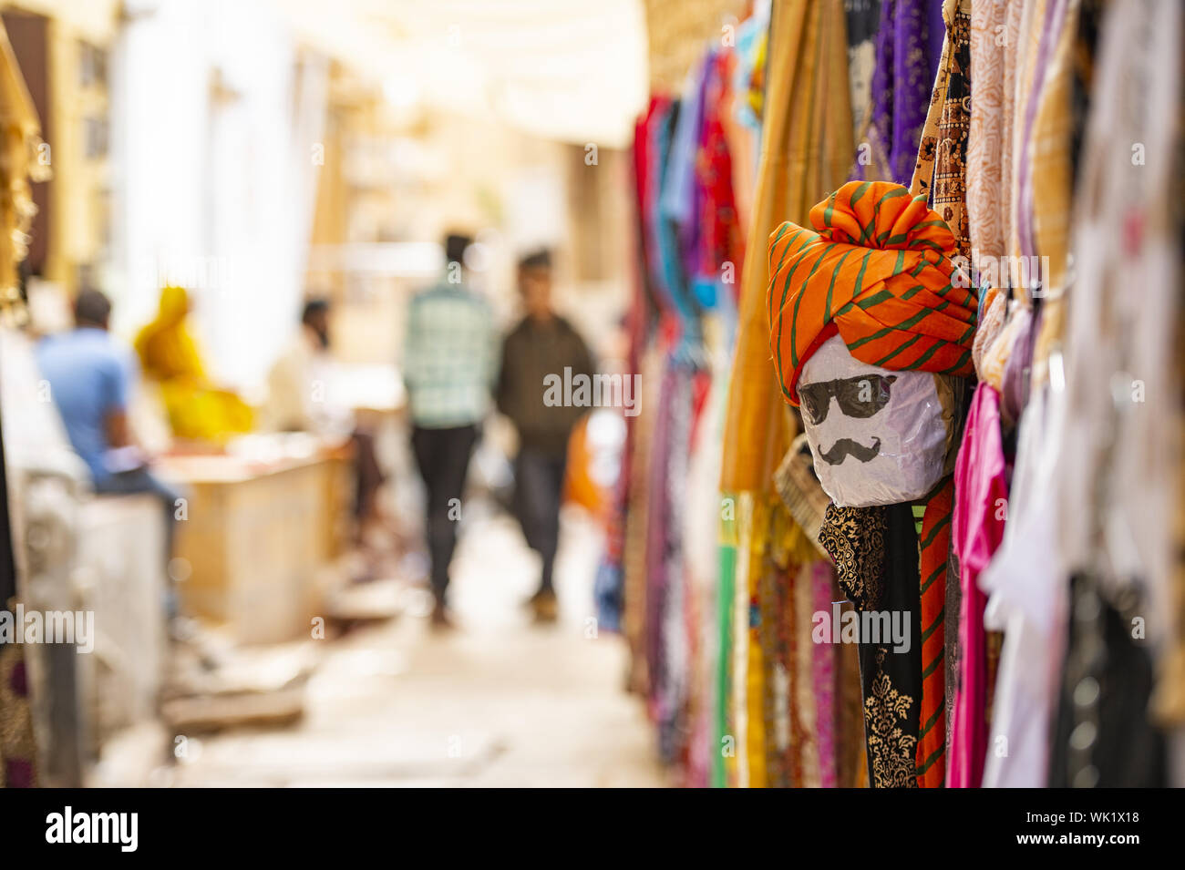 (Selektive Fokus) Schöner Shop mit bunte traditionelle indische Kleidung (Sari) und eine Maske zeigt das Gesicht einer Person aus Rajasthan. Jaisalmer, Indien Stockfoto