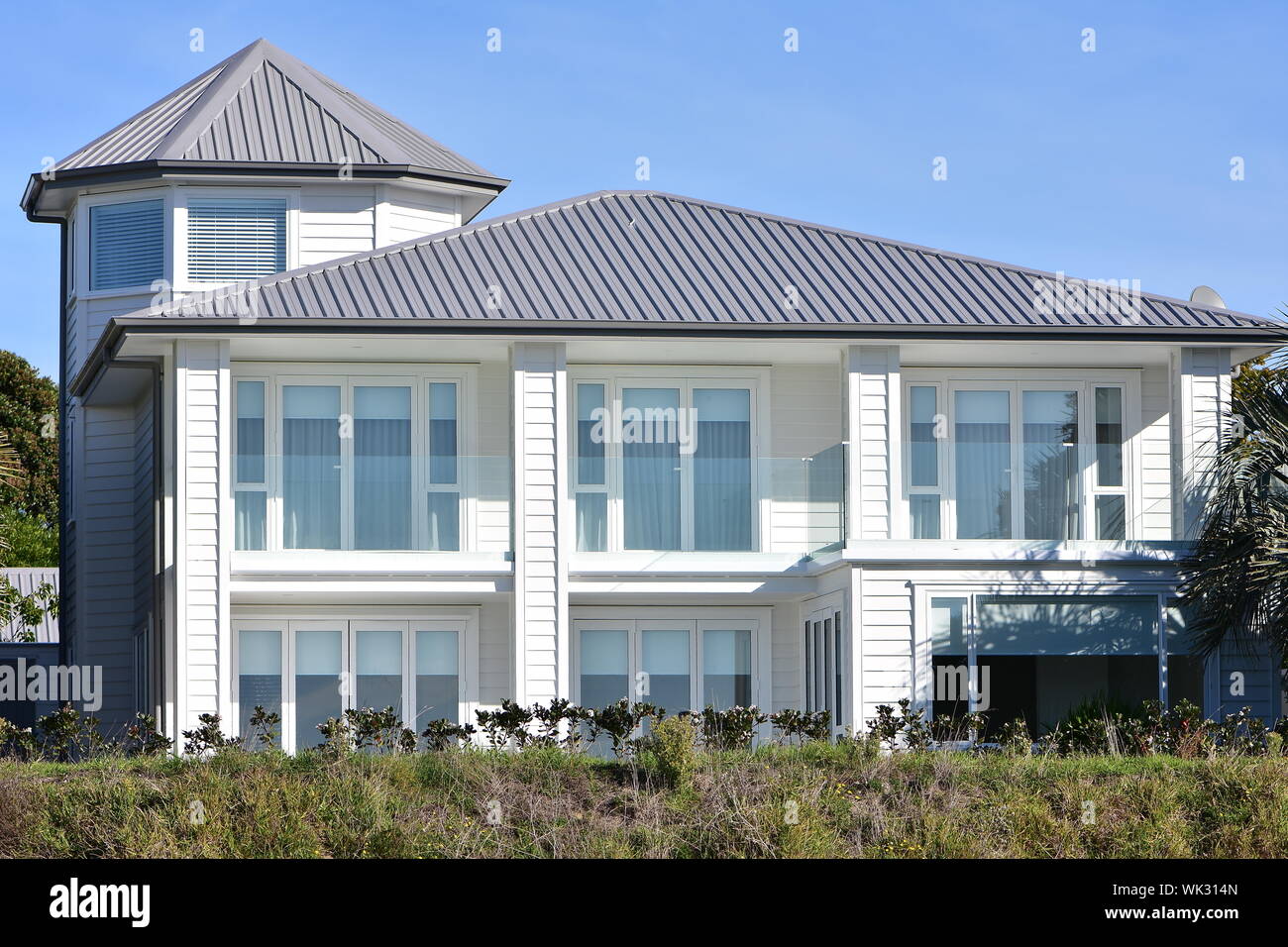 Großes zweistöckiges weißes Holzhaus mit meist Glaswände auf Fassade und Turm in der linken Ecke. Stockfoto