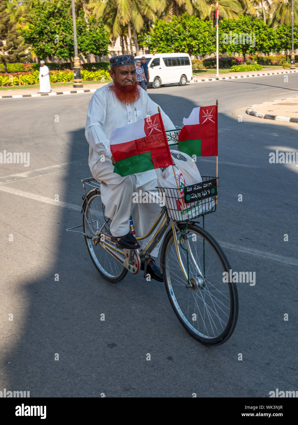 Maskat, Sultanat von Oman - 12. November 2017: Unbekannter Radfahrer auf einem Fahrrad mit Fahnen auf einer Straße in der Provinz Dhofar, Salalah, Oman. Stockfoto