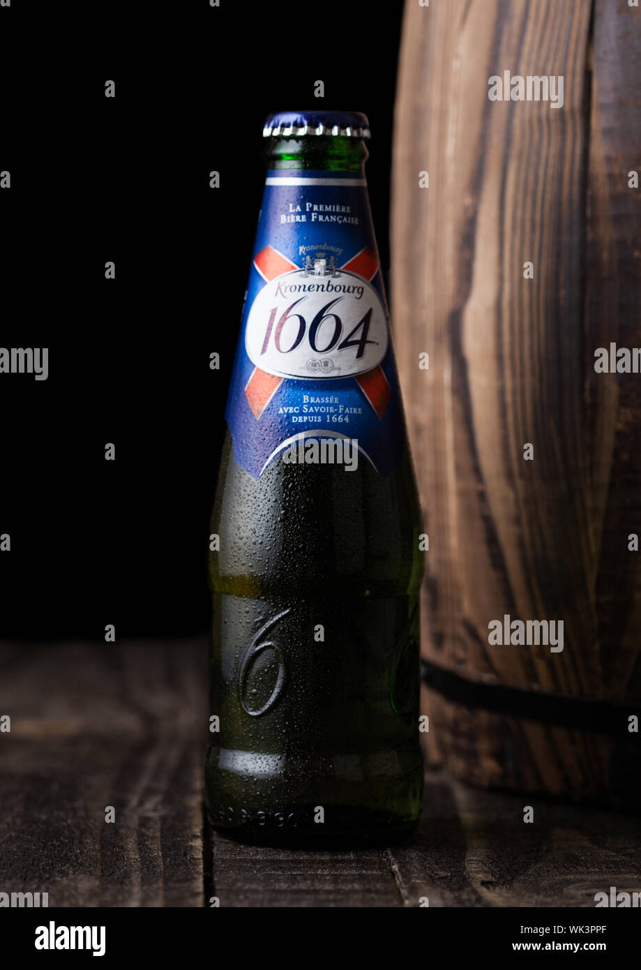 LONDON, Großbritannien - 10 August 2018: kalte Flasche Kronenbourg 1661 Bier neben Holzfass auf schwarzem Hintergrund. Stockfoto