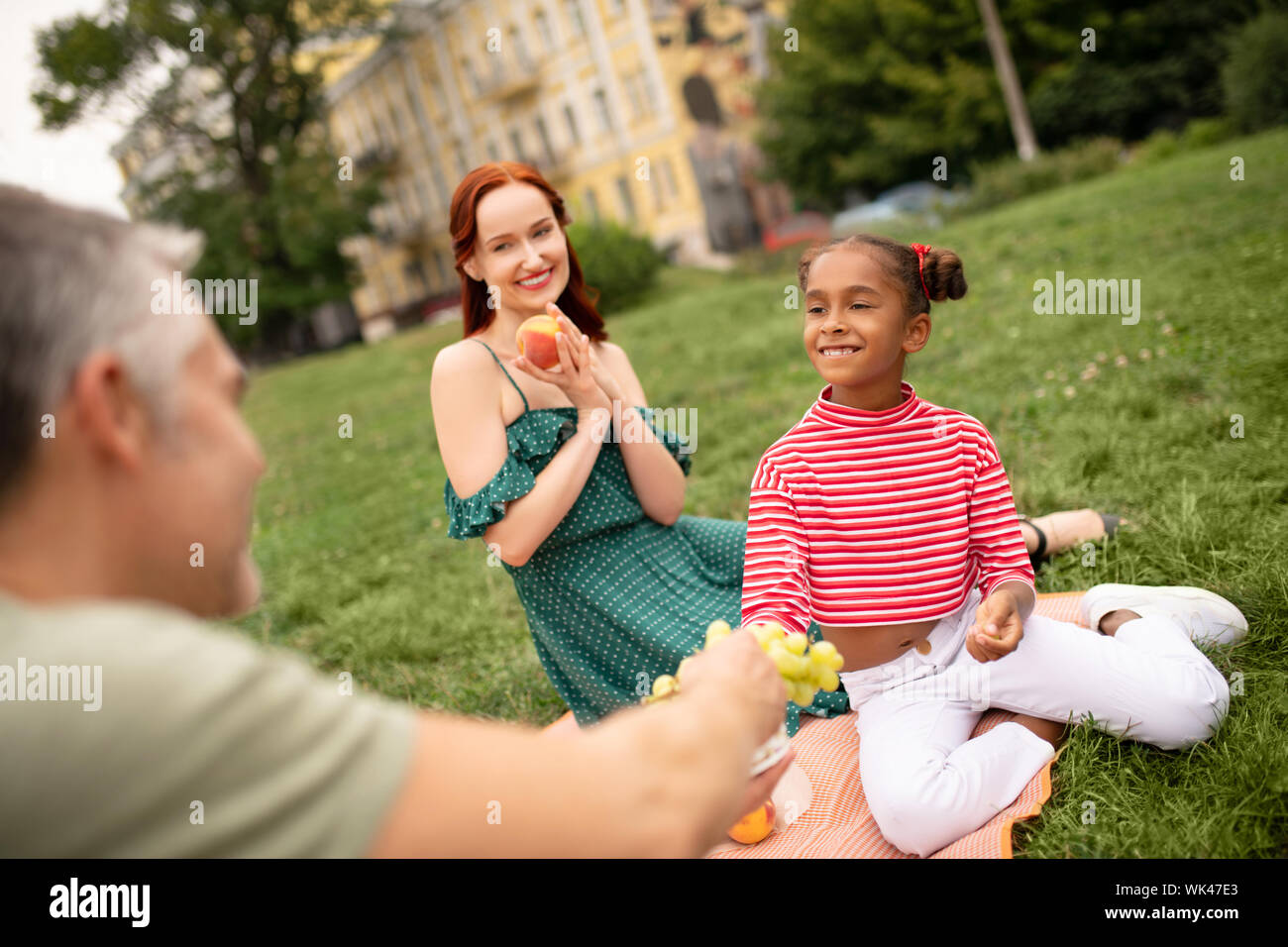 Mädchen lächelnd während der Einnahme von Trauben und in Familie Picknick Stockfoto