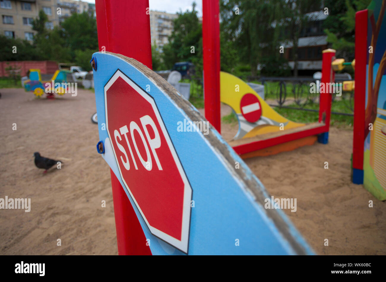 Red Road Sign top' in Miniatur schräg und dem Zeichen für "Keine Eingabe" auf dem Hintergrund der Spielplatz verschwommen Stockfoto