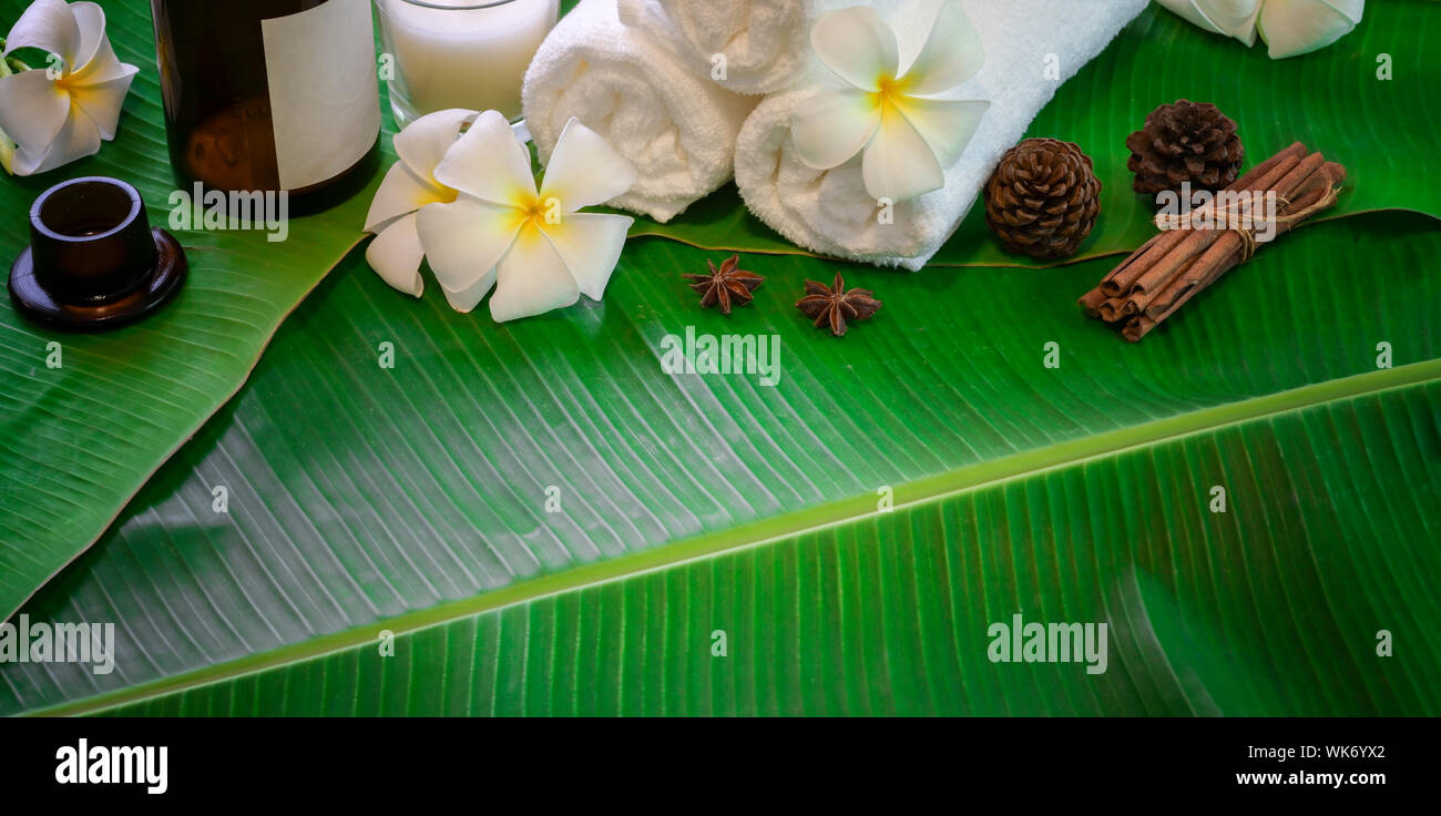 Spa Therapie Konzept: Blick von oben auf die schwarzen Steine und Handtücher für die Massage nach grüner Banane Blätter Hintergrund Stockfoto