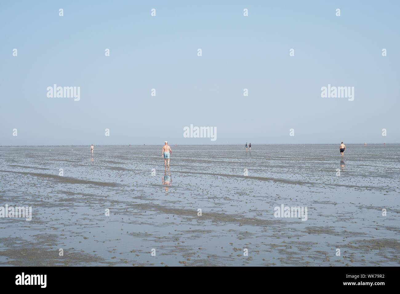 Cuxhaven, Deutschland - 26. August 2019: Nordsee bei Ebbe. Zufällige Menschen zu Fuß über Watt Watt. Stockfoto