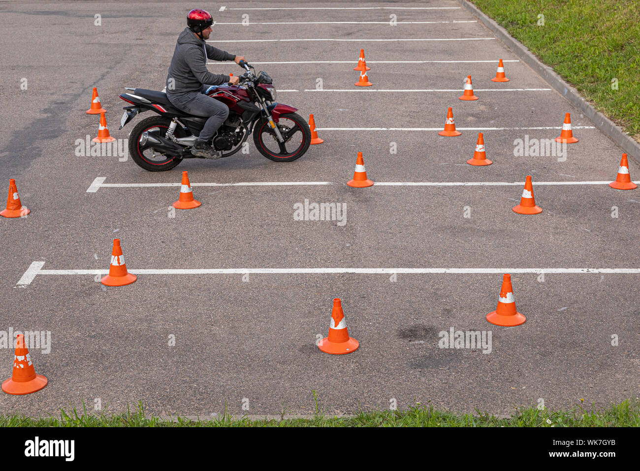 Minsk, Weißrussland - Juni, 2019. Mann in Helm auf Motor - Fahrrad üben am Parkplatz unter Leitkegel Stockfoto