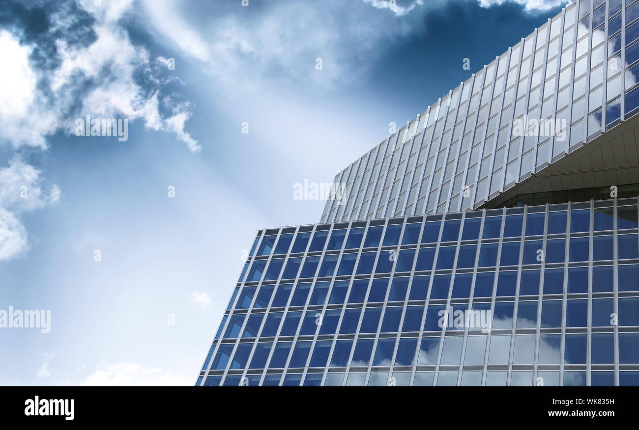Modernes Bürogebäude mit Glasoberfläche gegen blauen Himmel und Wolken. Das Büro schloss die Arbeit aus der Krise des Coronavirus zu Hause ab. Stockfoto