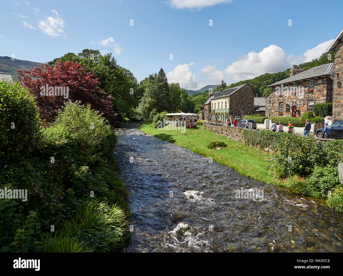 Häuser und den Fluss Glaslyn im Dorf Beddgelert an einem Sommertag, Snowdonia National Park, Gwynedd, Wales, Großbritannien Stockfoto