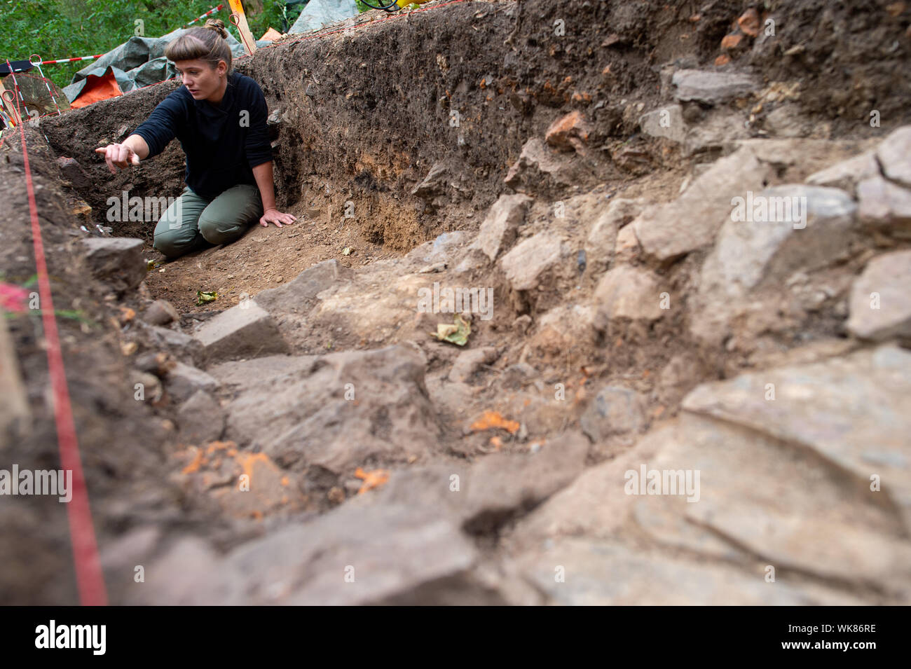 03 September 2019, Sachsen-Anhalt, Güntersberge: Die ausgrabung Regisseurin Anna Bartrow, Archäologe an der Universität Halle, hockt in einem Abschnitt der Ausgrabungsstätte "Wüstung Anhalt' und untersucht die Wand der Grube, in der sie vermutet, die Reste eines alten Ofens. Die Siedlung bedeckt etwa 11 Hektar und wurde zwischen dem 11. und dem 12. Jahrhundert gegründet. Das Dorf verlassen wurde bereits im 15. Jahrhundert. Das Dorf ist eine von ungefähr 100 im Harz, die während des Mittelalters verschwunden und sind nun verlassenen Gebieten genannt. Die Ausgrabungen sind wichtig, weil es schwer haben Stockfoto