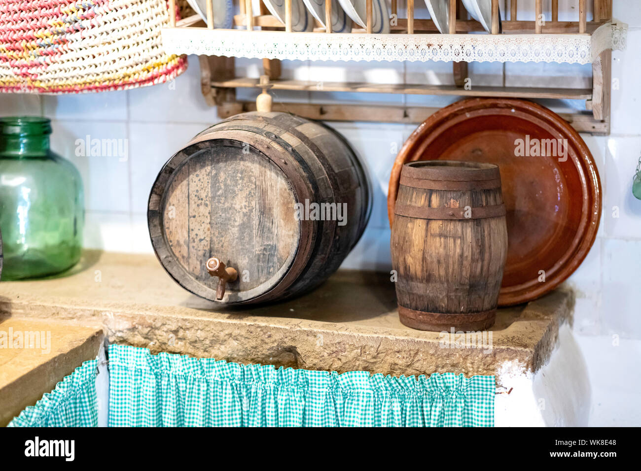 Stein Küche Tisch mit zwei Fässer, Gerichte und eine grüne Flasche, ein grünes Tuch im Erdgeschoss das Holz zu lagern Stockfoto