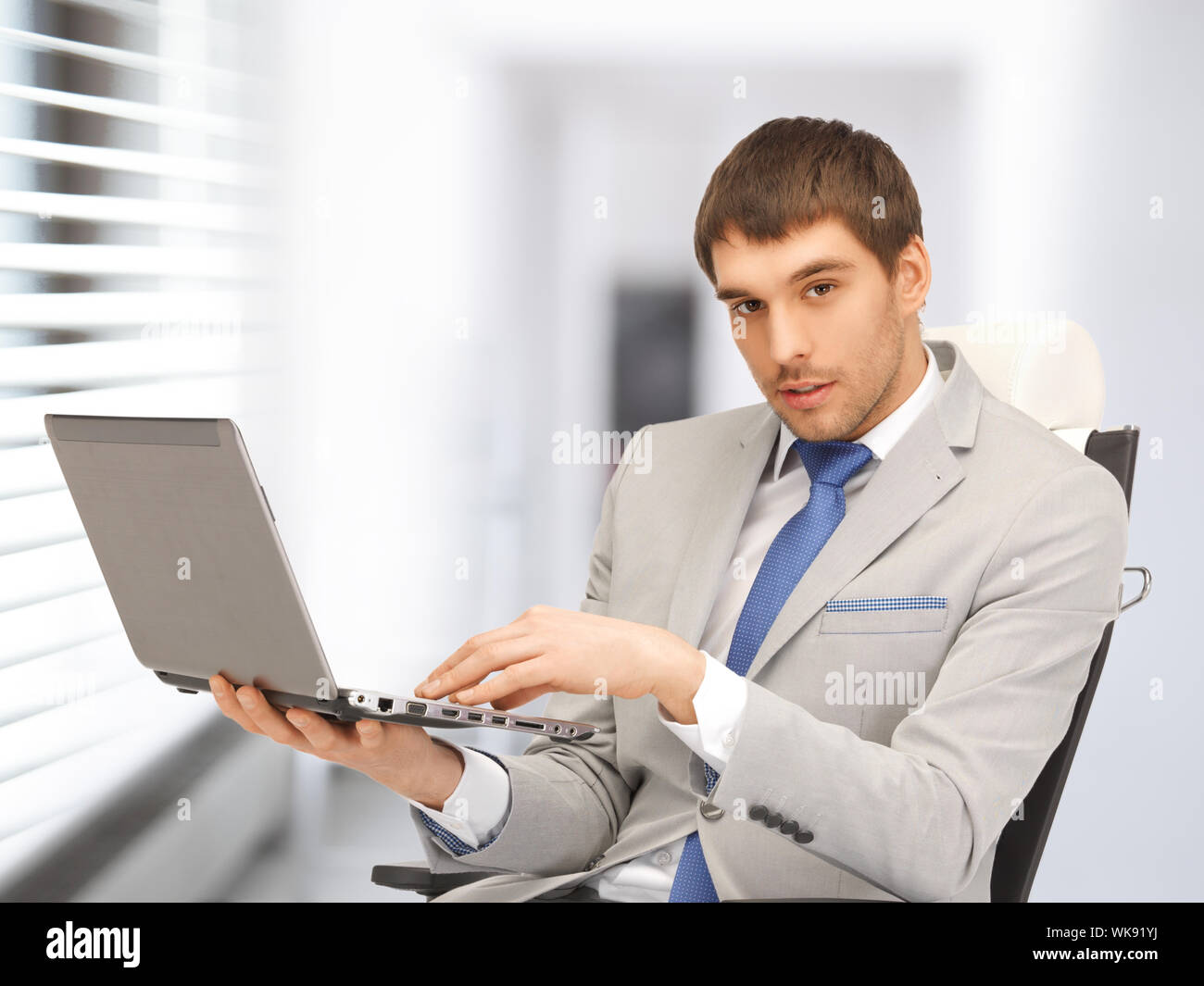 junger Geschäftsmann sitzt im Stuhl mit laptop Stockfoto