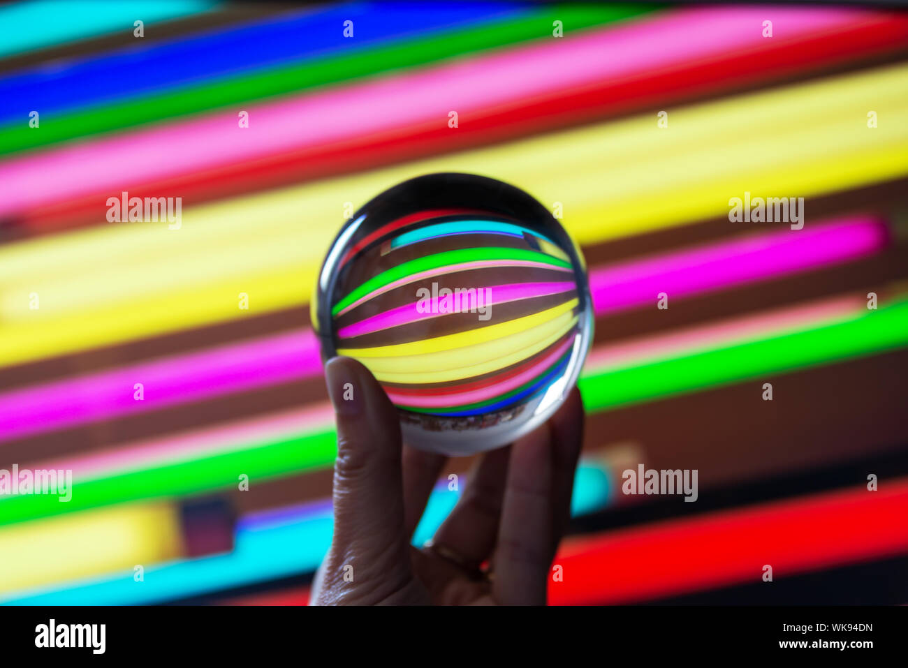 Reflexionen von farbigen Leuchtstoffröhren in eine Kristallkugel. Astract bunte Fotografie. Stockfoto