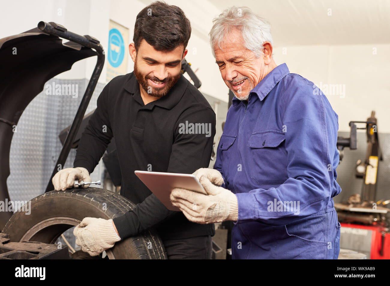 Auto Master als Ausbilder mit Mechatronik Lehrling auf Fehlerdiagnose mit Tablet-PC Stockfoto
