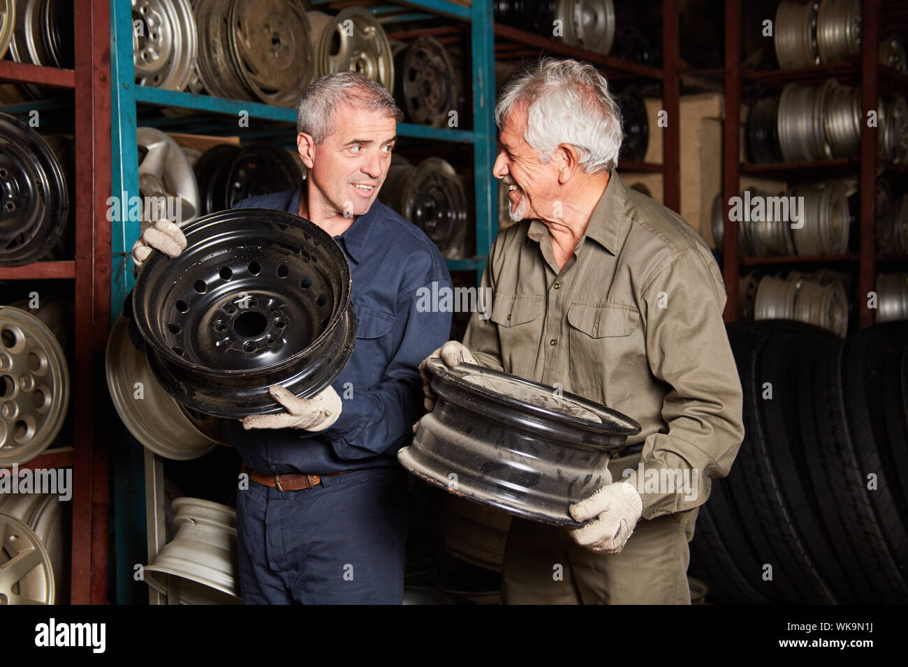 Zwei Mechaniker mit Felgen von Autos im Lager von einem Workshop Stockfoto