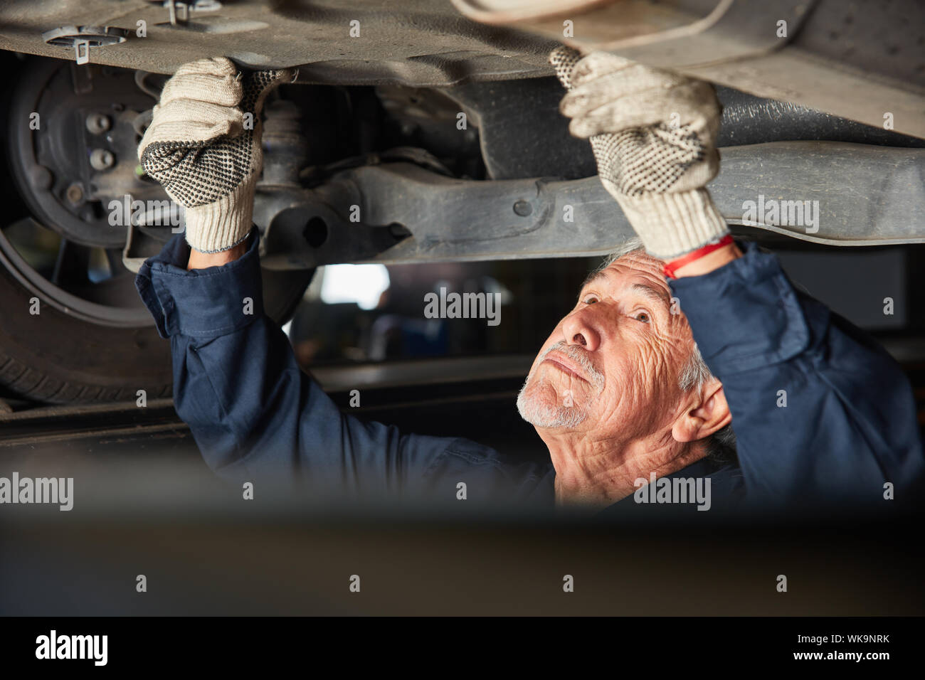 Erfahrener Mechaniker liegt in der autowerkstatt unter dem Auto in der Werkstatt Stockfoto