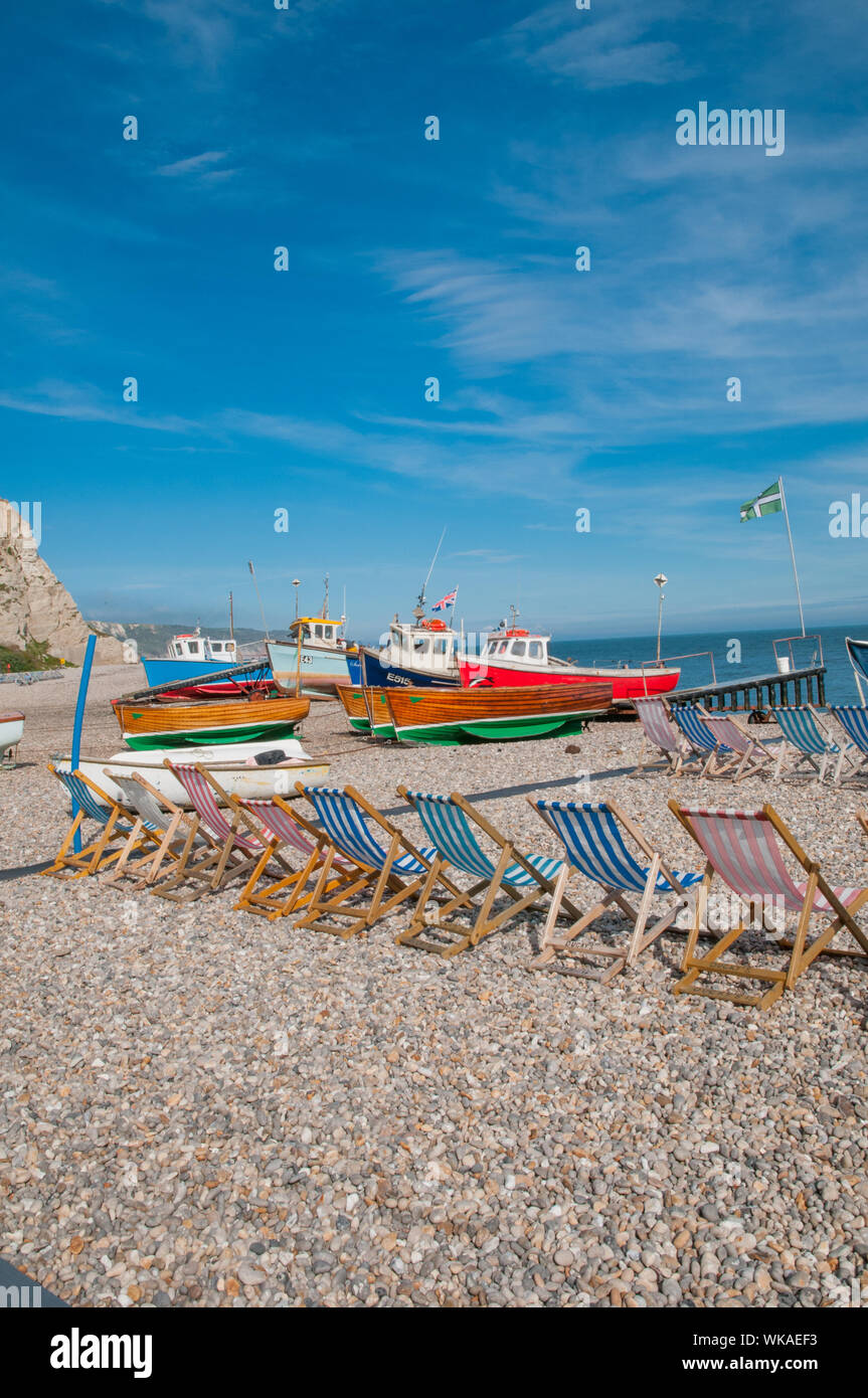 Liegestühle und Fischerboote am Strand Bier, Bier Devon England Stockfoto