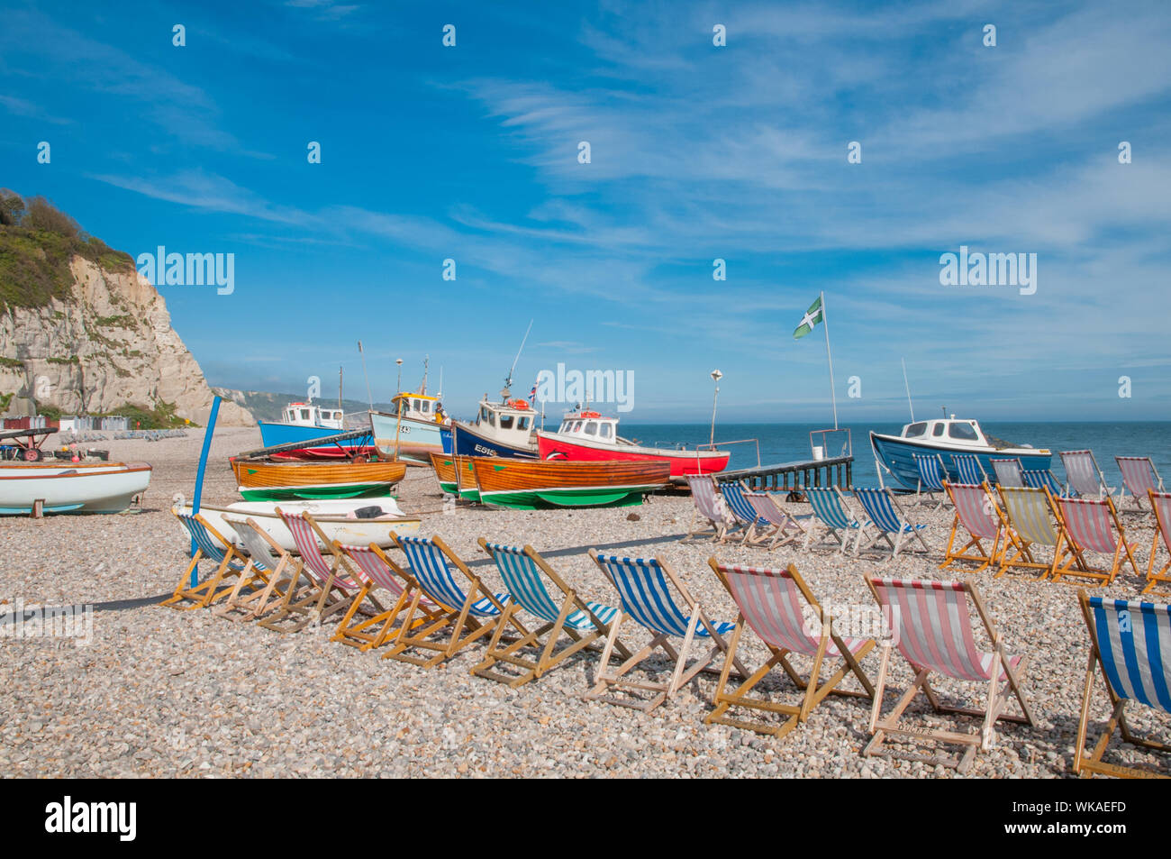 Liegestühle und Fischerboote am Strand Bier, Bier Devon England Stockfoto